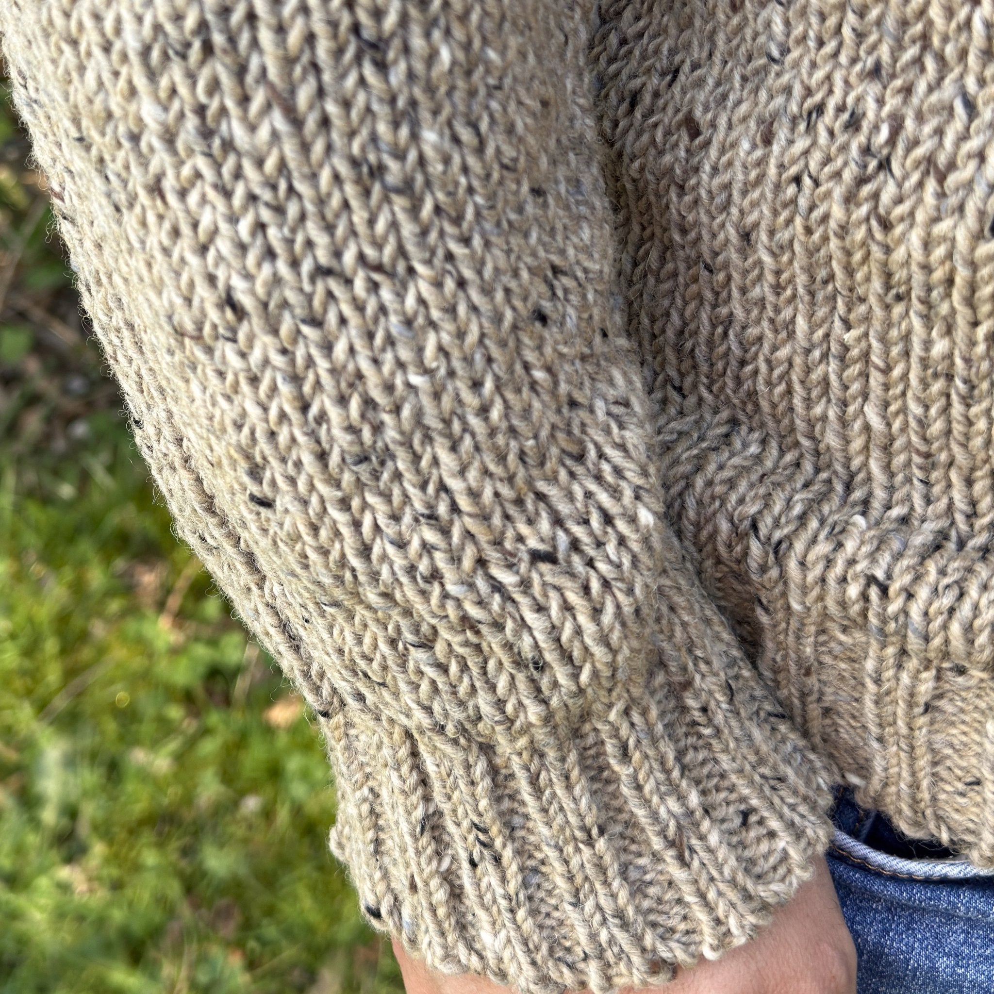 Close-up of men’s oatmeal Donegal wool sweater sleeve and ribbed cuff, showing textured knit and natural fleck detail, handcrafted in Ireland