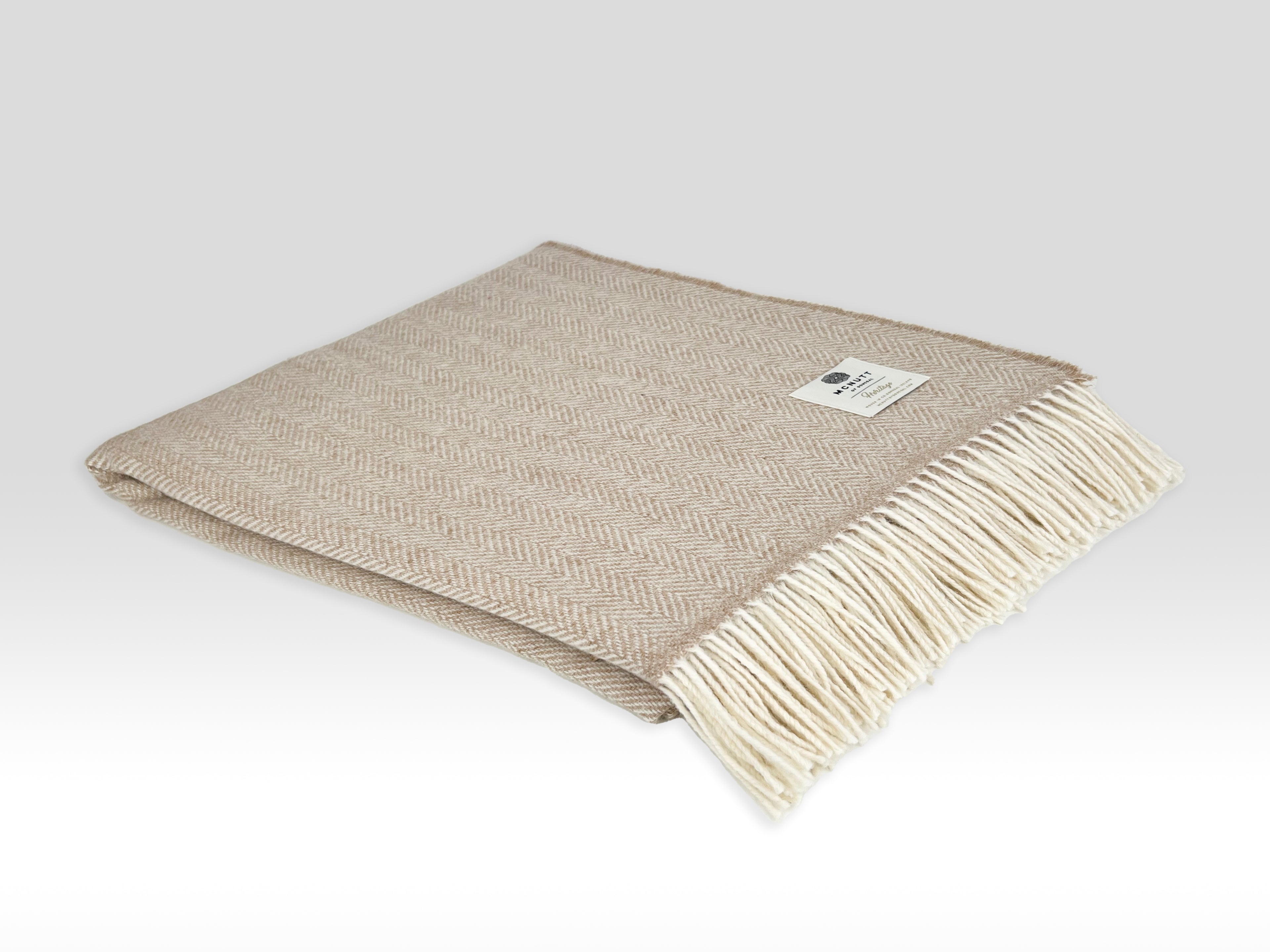 Beige woven blanket with white fringe on a light gray background