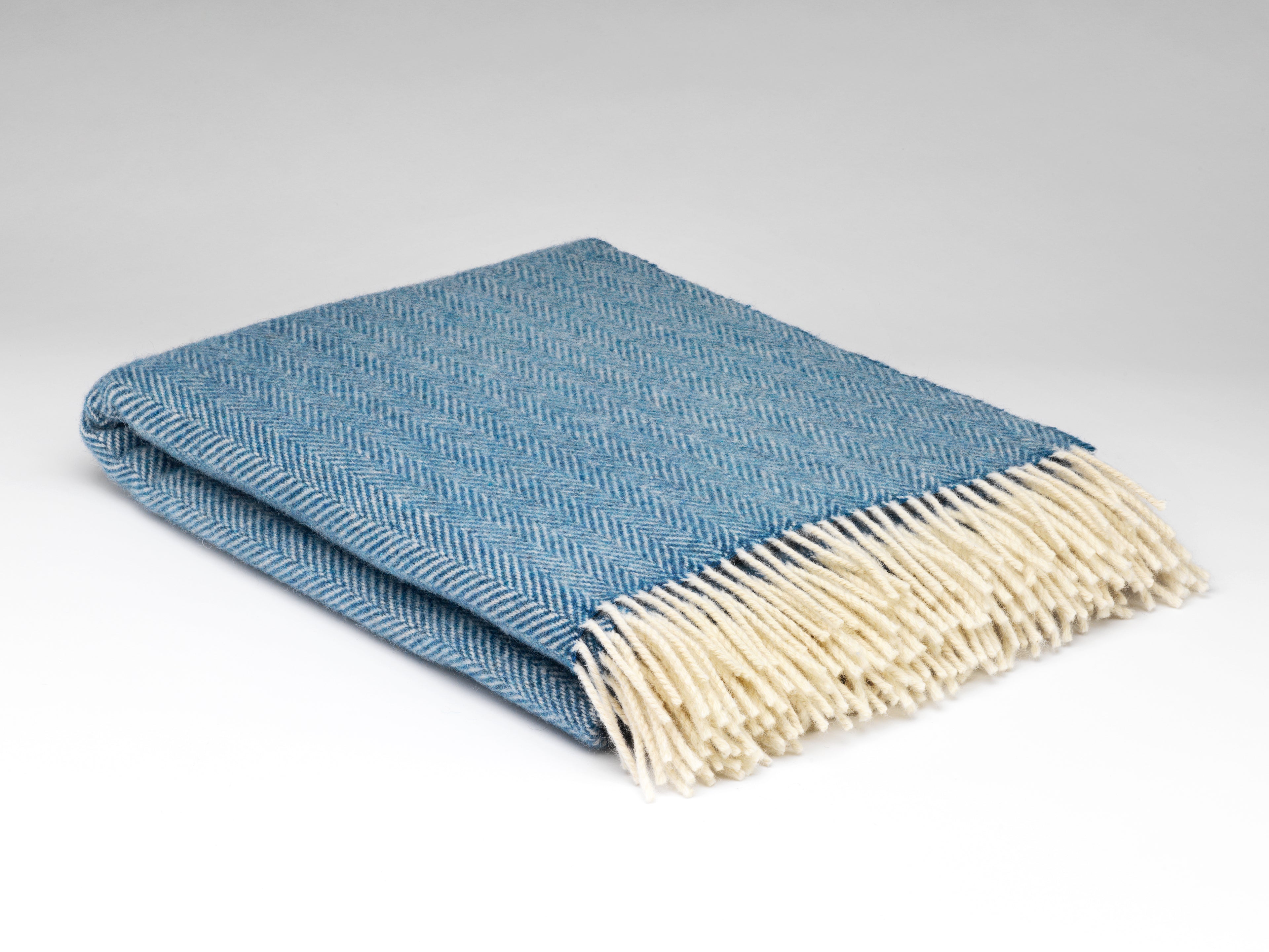 Blue blanket with white fringe on a light gray background