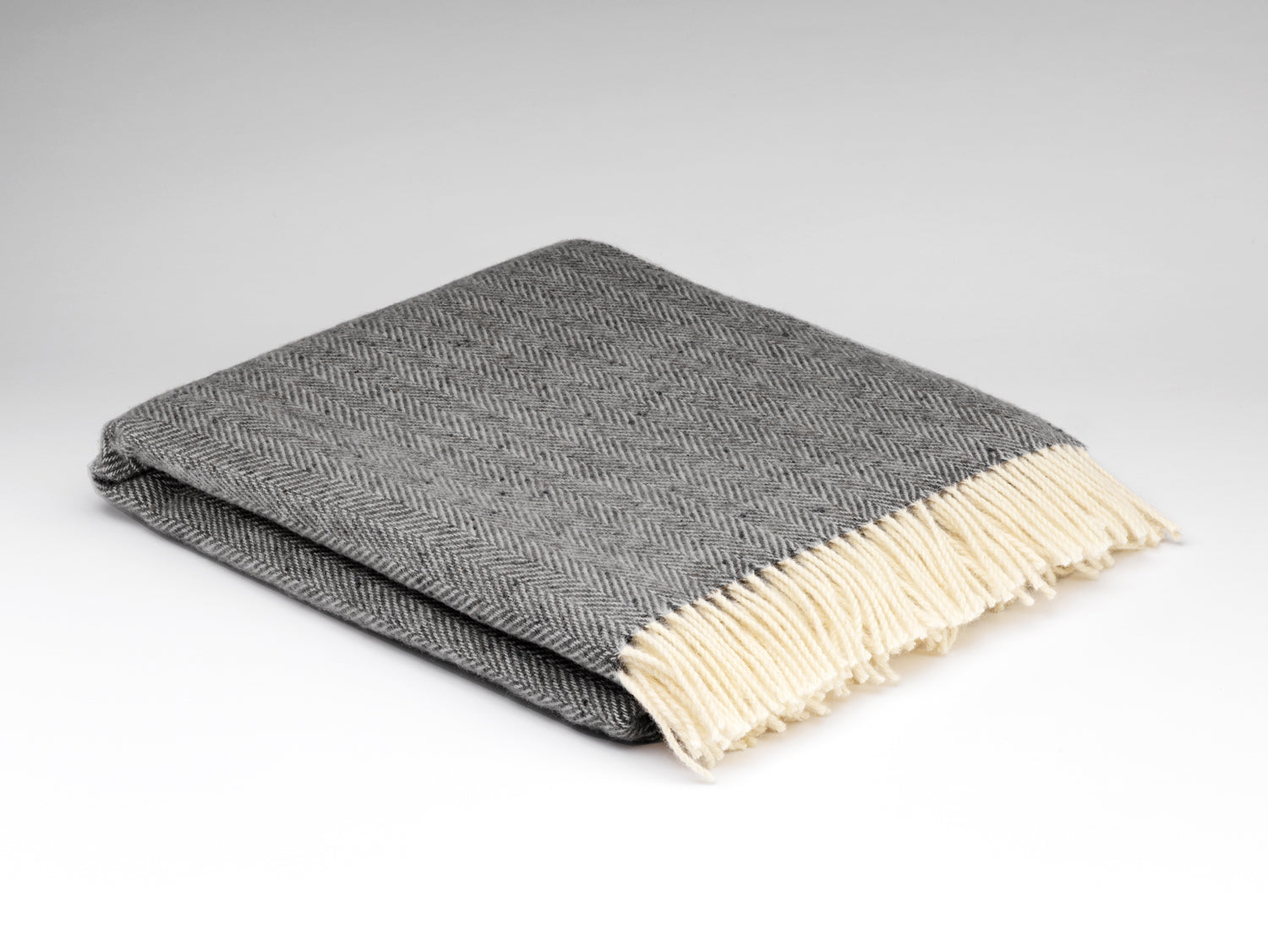Gray blanket with beige fringe on a light gray background